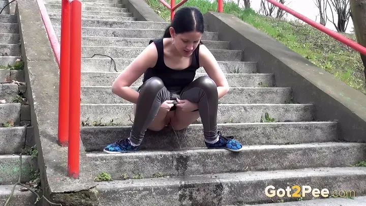 Brunette Splashes A Golden Piss Down Concrete Steps